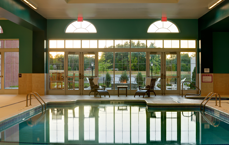 Indoor pool with skylights surround by lounge chairs