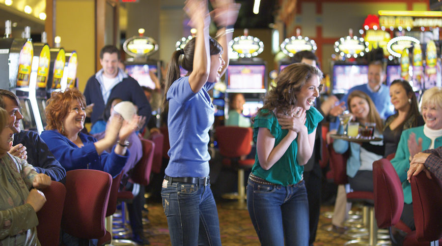 Two women standing up and cheering in front of slot machines