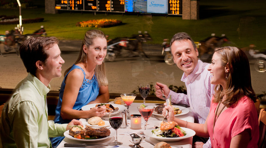 Two couples dining at Fortunes restaurant while overlooking live harness racing